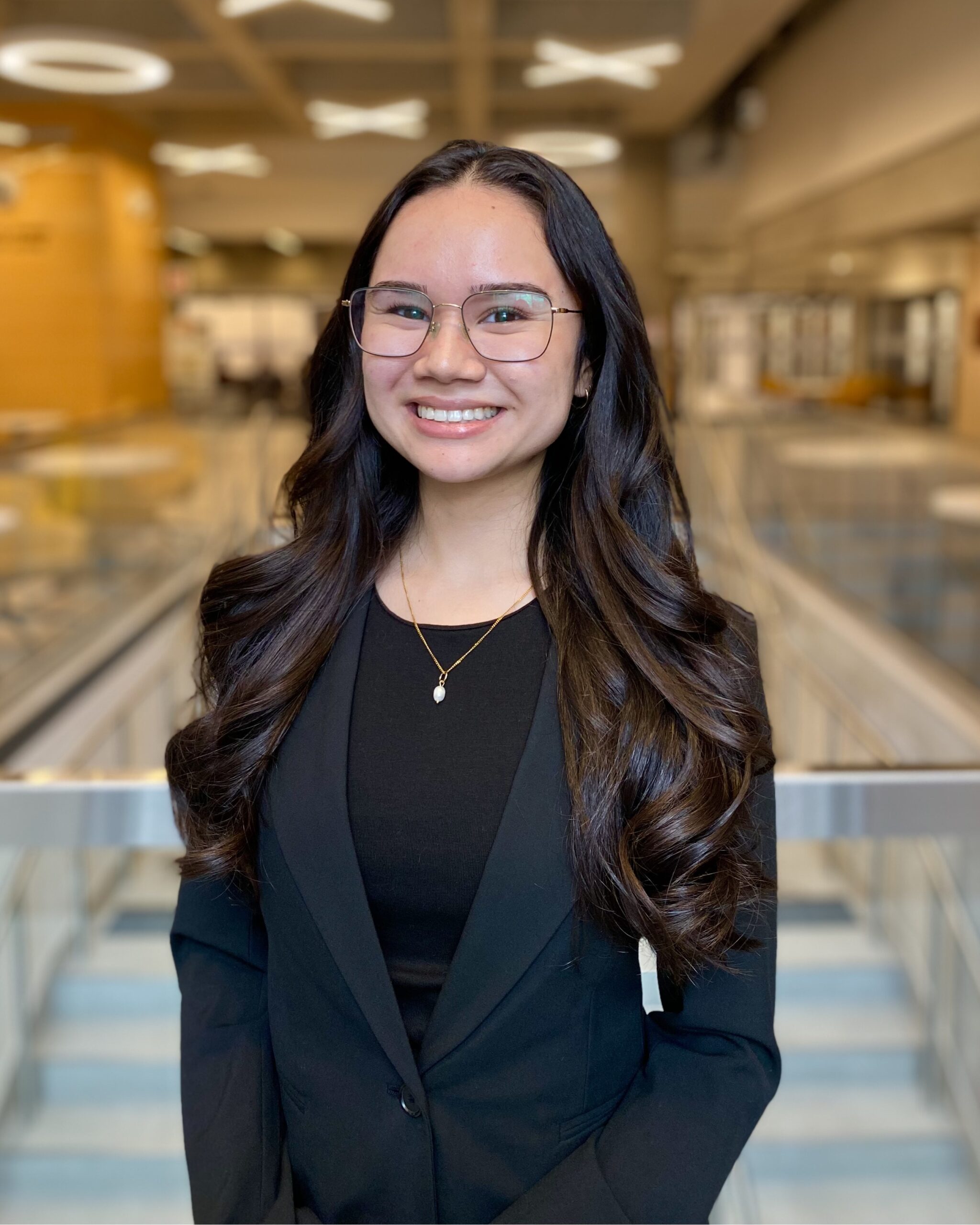 Headshot of London family law student Sabrina Bernard smiling at the camera standing in a modern, professional building atrium